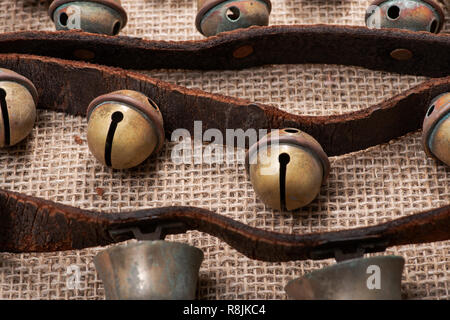 Antique vintage ossidare ottone sleigh bells sul cinturino in pelle e tela sfondo Foto Stock