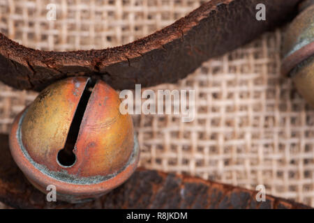 Antique vintage ossidare ottone sleigh bells sul cinturino in pelle e tela sfondo Foto Stock