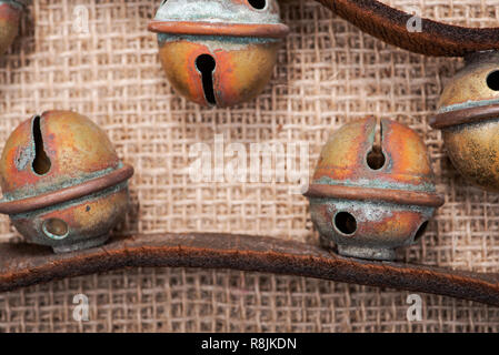 Antique vintage ossidare ottone sleigh bells sul cinturino in pelle e tela sfondo Foto Stock