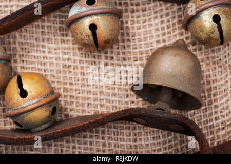 Antique vintage ossidare ottone sleigh bells sul cinturino in pelle e tela sfondo Foto Stock