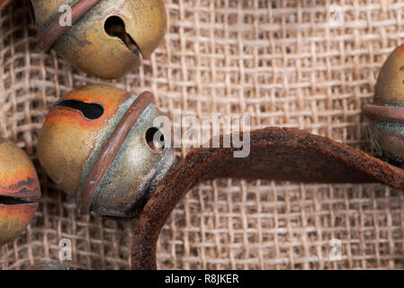 Antique vintage ossidare ottone sleigh bells sul cinturino in pelle e tela sfondo Foto Stock