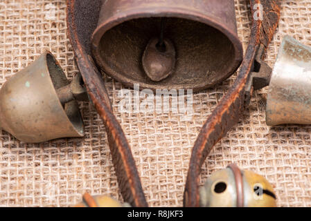 Antique vintage ossidare ottone sleigh bells sul cinturino in pelle e tela sfondo Foto Stock