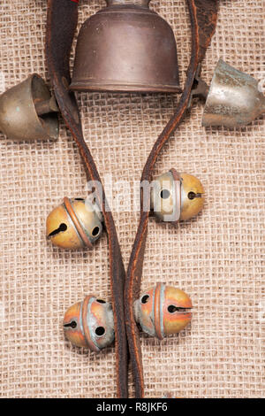 Antique vintage ossidare ottone sleigh bells sul cinturino in pelle e tela sfondo Foto Stock