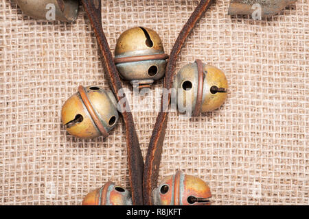 Antique vintage ossidare ottone sleigh bells sul cinturino in pelle e tela sfondo Foto Stock