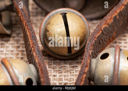 Antique vintage ossidare ottone sleigh bells sul cinturino in pelle e tela sfondo Foto Stock