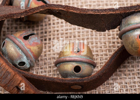 Antique vintage ossidare ottone sleigh bells sul cinturino in pelle e tela sfondo Foto Stock