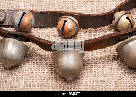 Antique vintage ossidare ottone sleigh bells sul cinturino in pelle e tela sfondo Foto Stock