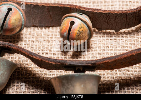 Antique vintage ossidare ottone sleigh bells sul cinturino in pelle e tela sfondo Foto Stock