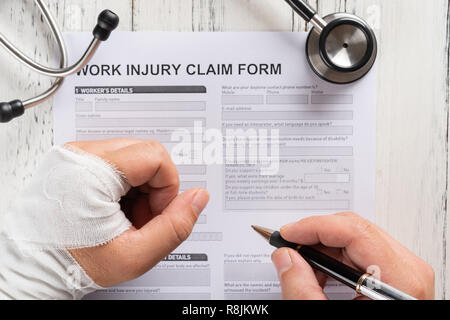 Vista dall'alto uomo riempiendo un pregiudizio di lavoro modulo di reclamo con uno stetoscopio medico e concetto di assicurazione Foto Stock