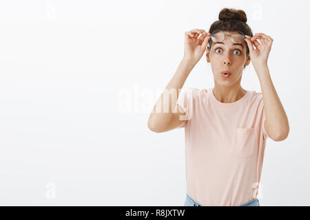 Sorpresa, le espressioni del viso e il concetto di popolo. Emozionato divertito e incuriosito femmina giovane collaboratore di decollare bicchieri al check out awesome outfit di amico labbra pieghevole stupiti popping occhi alla fotocamera Foto Stock