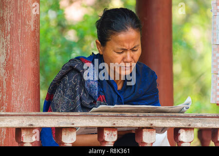Una bella donna di legge il suo giornale presso il tempio di Wat Phnom, in Phnom Penh Cambogia Foto Stock