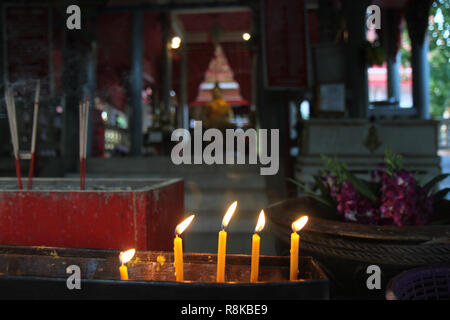 Buddisti di rendere merito,posizionando una candela accesa e incenso illuminato con candele telaio sull altare del Buddha a tempio. Messa a fuoco selettiva. Foto Stock