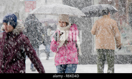 A Belgrado, in Serbia - Dicembre 15, 2018: Una ragazza adolescente camminare sotto ombrellone in forte nevicata in città strada folla Foto Stock