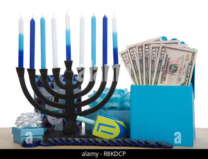 Hanukkah menorah con candele, dreidel, monete e presenta su di un legno chiaro tavolo. Casella farcite con 50 le fatture del dollaro. Che rappresenta il costo delle vacanze Foto Stock