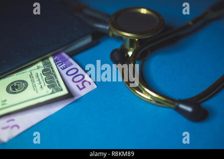 Dollari ed Euro dal blocco note e uno stetoscopio sul tavolo. Il concetto di bustarelle per medici, corrompete un revisore, la corruzione in medicina. Foto Stock