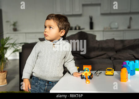 Kid giocare con modellini di auto a tavola nel salotto di casa Foto Stock