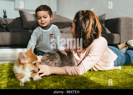 Madre e Figlio la posa sul pavimento con il cane e il gatto nel salotto di casa Foto Stock