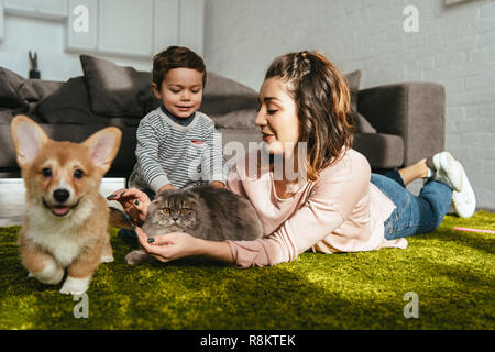 Donna attraente e little boy posa sul pavimento con il cane e il gatto nel salotto di casa Foto Stock