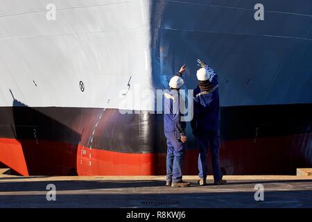 Francia, Finisterre, Concarneau, dei lavoratori di fronte alla prua di una nave durante il suo lancio Foto Stock