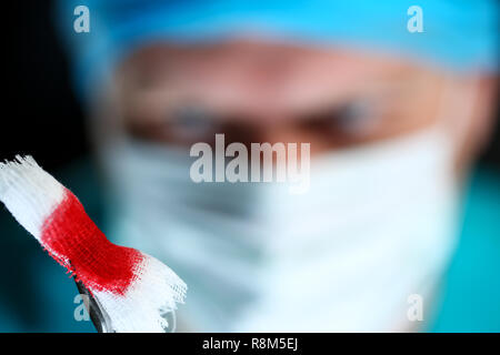 Medico chirurgo in sterili bracci uniforme tenendo gli utensili con materiale bio Foto Stock