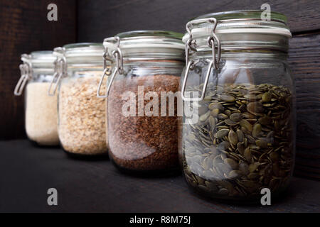 Diversi semi in vasi di storage nella dispensa, legno scuro dello sfondo. Elegante cucina organizzazione Foto Stock