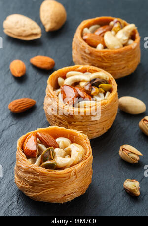 Medio tradizionali dolci orientali "Bird's Nest' in sciroppo di miele con dado riempimento - mandorle, anacardi, pistacchi. Il baklava di close-up. Deliziosi dessert. S Foto Stock