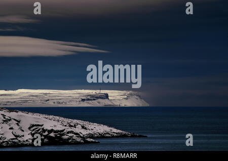 Frosty paesaggio notturno l'Oceano Artico. Northern grave natura freddo scogliere. Buio profondo blu acqua e cielo, il bianco delle nuvole, nero costa rocciosa riva. Il mare di Barents, penisola di Kola Teriberka, Russia. Foto Stock