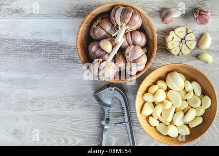 Aglio fresco teste, set di chiodi di garofano in lastra su un grigio chiaro superficie in legno, vista dall'alto, copiare lo spazio, lo spazio libero per il testo. Foto Stock