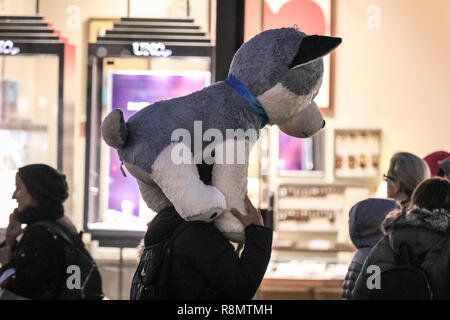 Regent Street, Londra, 16 dic 2018. Una shopper porta intorno ad un enorme kuddly cucciolo giocattolo sulle sue spalle. Su una delle più frequentate durante i fine settimana prima di Natale, la folla degli acquirenti di passeggiare lungo Regent Street con i suoi tanti colorati visualizza la finestra. Credito: Imageplotter News e sport/Alamy Live News Foto Stock