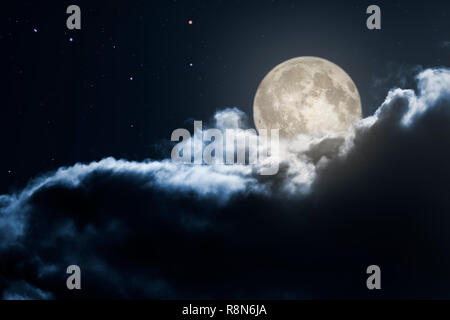 Luna piena che emergono da dietro le nuvole scure Foto Stock