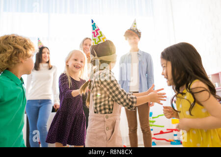 Gli occhi bendati ragazza tenta di toccare gli altri giocatori Foto Stock