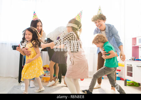 Genitori felici giocando blind mans buff con i loro figli Foto Stock