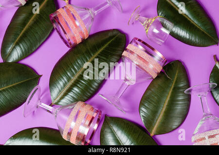 Appartamento laici sfondo ultravioletta con bicchieri di vino e verde foglie tropicali. Foto Stock