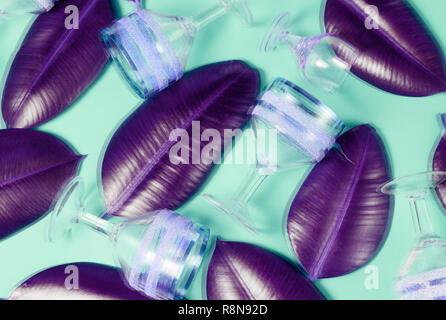 Abstract background olografico effetto sul layout con vuoto vintage bicchieri di vino e verde foglie tropicali di ficus. Foto Stock