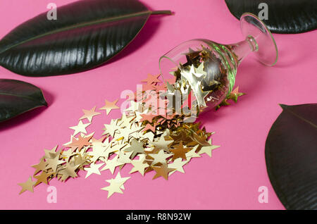 Sfondo rosa con bicchieri di vino e verde foglie tropicali. Foto Stock