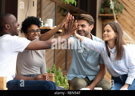 Felice multietnica amici dando alta cinque, festeggiare il successo Foto Stock