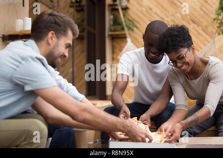 Sorridente multietnica diversi amici prendendo fette di pizza da box Foto Stock