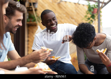 Happy amici mangiare la pizza insieme, ridere divertente scherzo Foto Stock