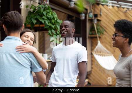 Felice di ridere amici abbracciando nella riunione dopo un lungo periodo di tempo Foto Stock