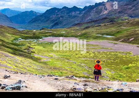 Donna Peruviana vestito in abiti tradizionali cercando su un paesaggio panoramico nelle Ande intorno Ausangate e Rainbow Montagne (Vinicunca), Perù Foto Stock