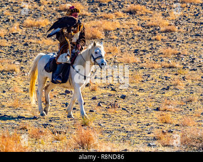 ULGII, MONGOLIA - Ottobre 6, 2018 : il mongolo Golden Eagle Hunter nel tradizionale pelliccia di volpe abbigliamento seduta a cavallo con il ben addestrato golden ea Foto Stock