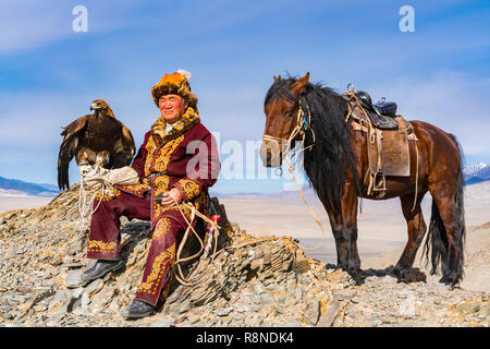 ULGII, MONGOLIA - Ottobre 9, 2018 : il mongolo Golden Eagle cacciatore con il suo cavallo e un ben addestrato golden eagle seduti sulla cima della montagna pronto Foto Stock