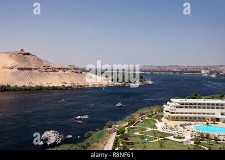 Una vista del Nilo, con le tombe dei nobili (L) sulla sponda ovest del Nilo e il Movenpick Resort (R) ad Aswan, Egitto. Foto Stock