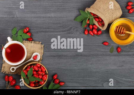 Tè con rosa canina e miele su un di legno nero con sfondo copia dello spazio per il tuo testo. Vista superiore Foto Stock