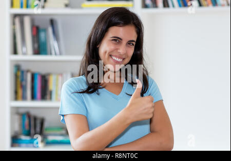 La donna araba che mostra il pollice fino al coperto a casa Foto Stock