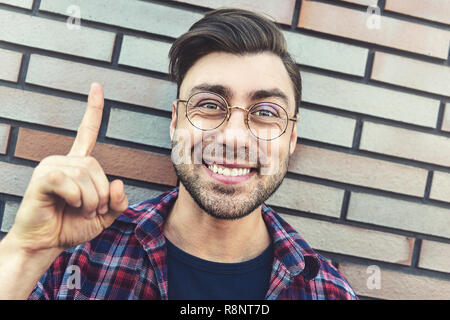 Grande idea! Uomo bello mantenendo il dito puntato verso l'alto, mostrando qualcosa sopra la sua testa, rendendo gesto con il dito indice. Eureka, segno della soluzione con Foto Stock