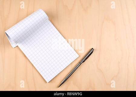 Carta Blocco note e penna a sfera su un tavolo di legno. Foto Stock