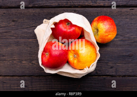 Rifiuti Zero a fare la spesa. Pacchetto-frutta gratis scuro sul tavolo di legno con texture. Mele fresche in Eco borse in cotone. Plastica-pacchetto gratuito Foto Stock