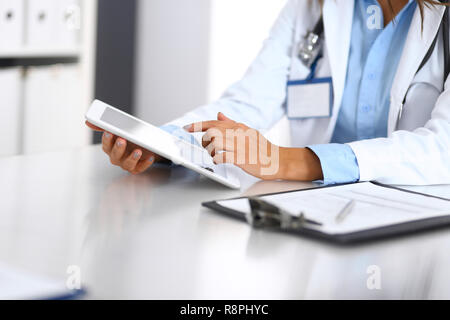 Medico sconosciuto donna utilizzando computer tavoletta mentre diritte in piedi vicino alla finestra in ospedale, close-up di mani. Medicina e salute concetto di cura Foto Stock