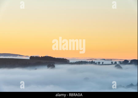 Sul confine tra Inghilterra e Galles nei pressi di Knighton, Powys, Regno Unito. Vista serale a ovest da Stonewall Hill mostra le valli riempiti con una fitta nebbia Foto Stock